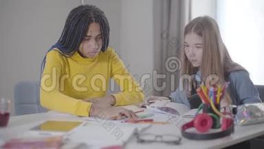 两个朋友<strong>一起</strong>在室内学习。 非裔美国人和白人女孩坐在桌子旁<strong>写</strong>作。 教育